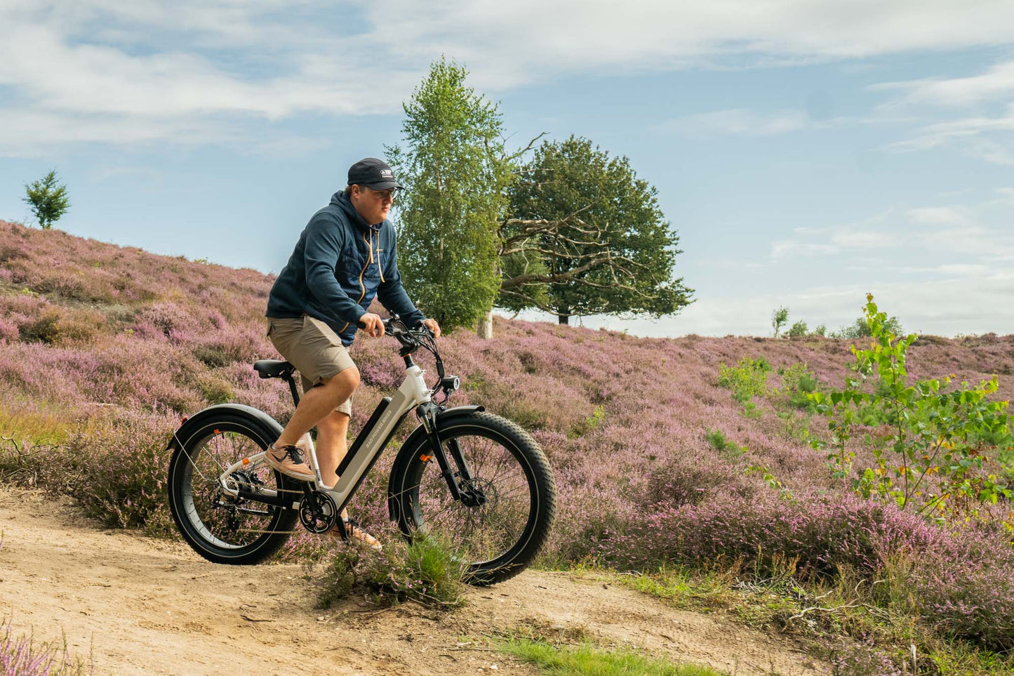 Male riding the white RadRhino 6 Plus Step-Thru bike in nature