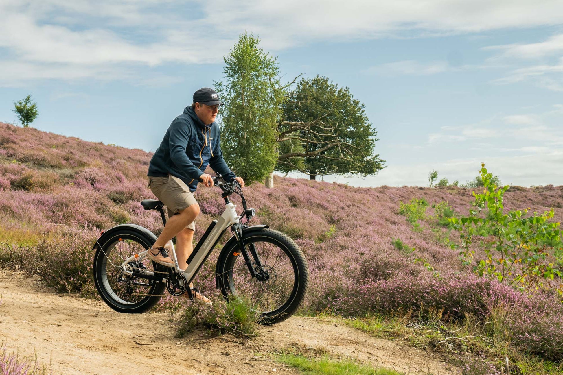 Male riding the white RadRhino 6 Plus Step-Thru bike in nature